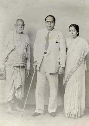 Studio photograph: Sant Gadge Baba with a staff, Dr B. R. Ambedkar in a light suit, and Dr Savita Ambedkar in a sari.